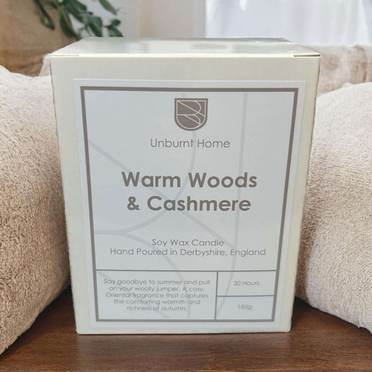 Cashmere candle in box on hard word surface with cashmere material in the background.