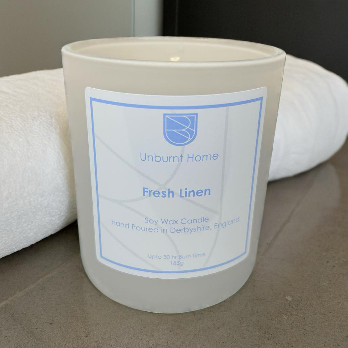 Fresh Linen Candle on dark stone surface with fresh linen in the background