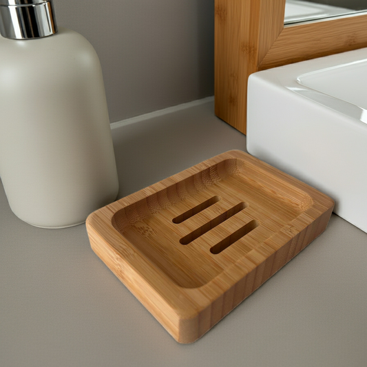 A bamboo soap disk on a neutral colored bathroom counter top with sink, mirror and soap dispenser