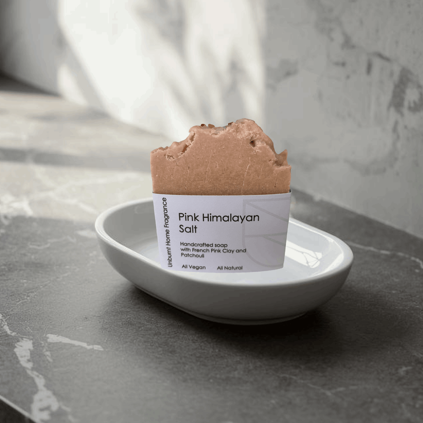 Pink Himalayan salt soap on a white porcelain soap dish on a stylish bathroom counter top