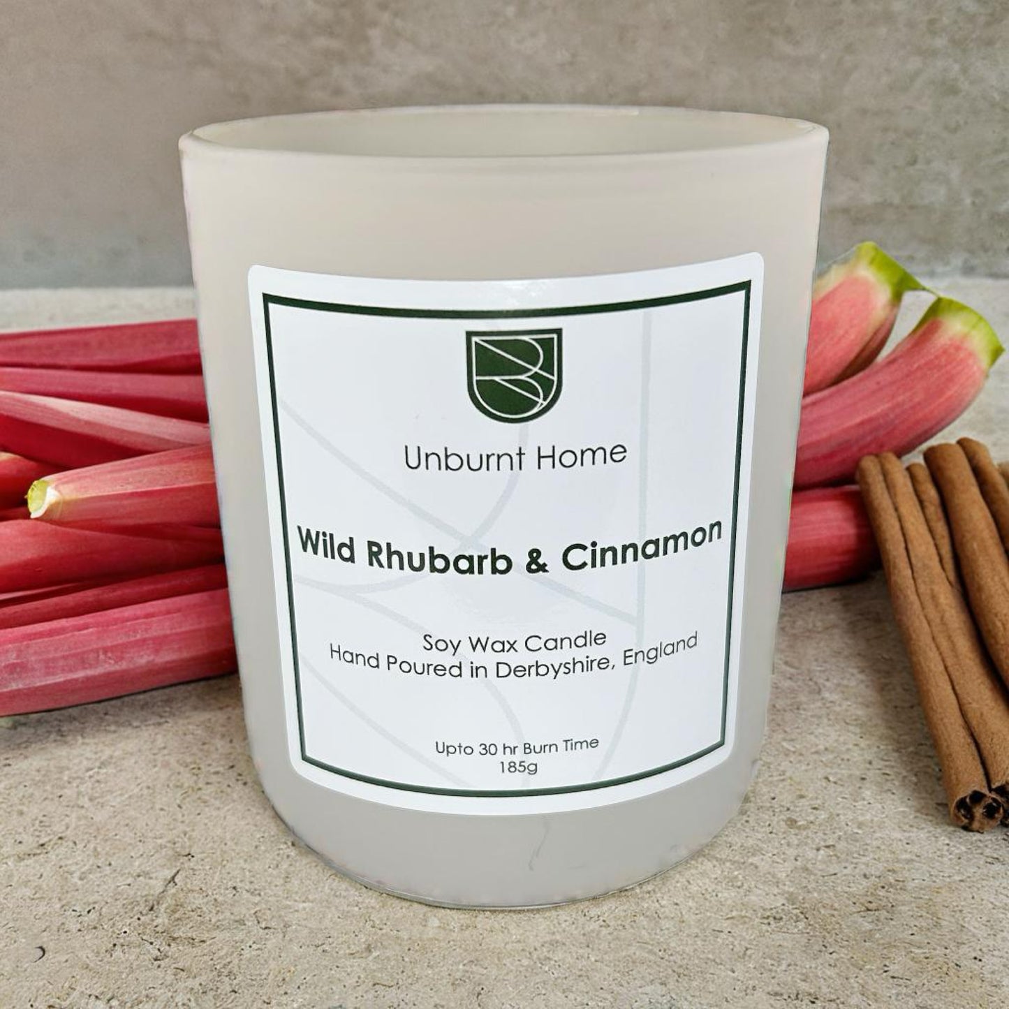 Rhubarb candle on stone surface with rhubarb and cinnamon in the background