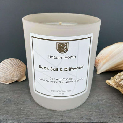Sea Salt Candle on dark wood surface with shells in the background