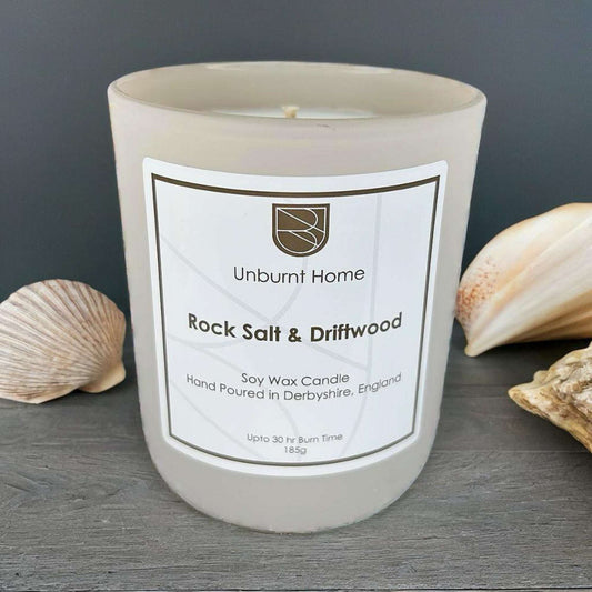 Sea Salt Candle on dark wood surface with shells in the background