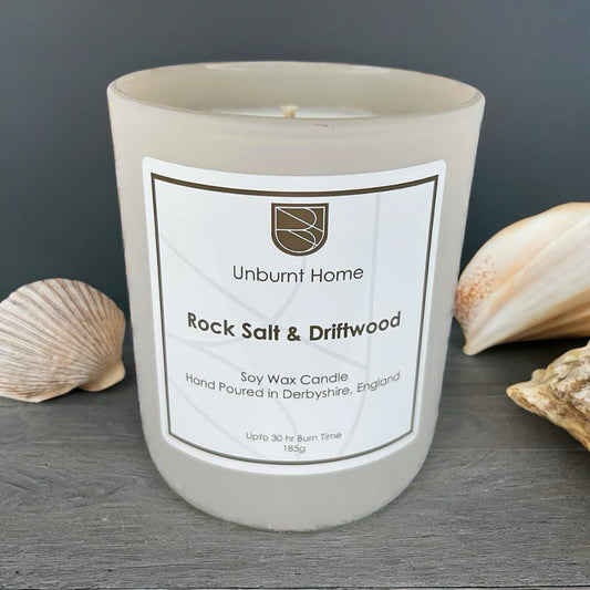 Sea Salt Candle on dark wood surface with shells in the background